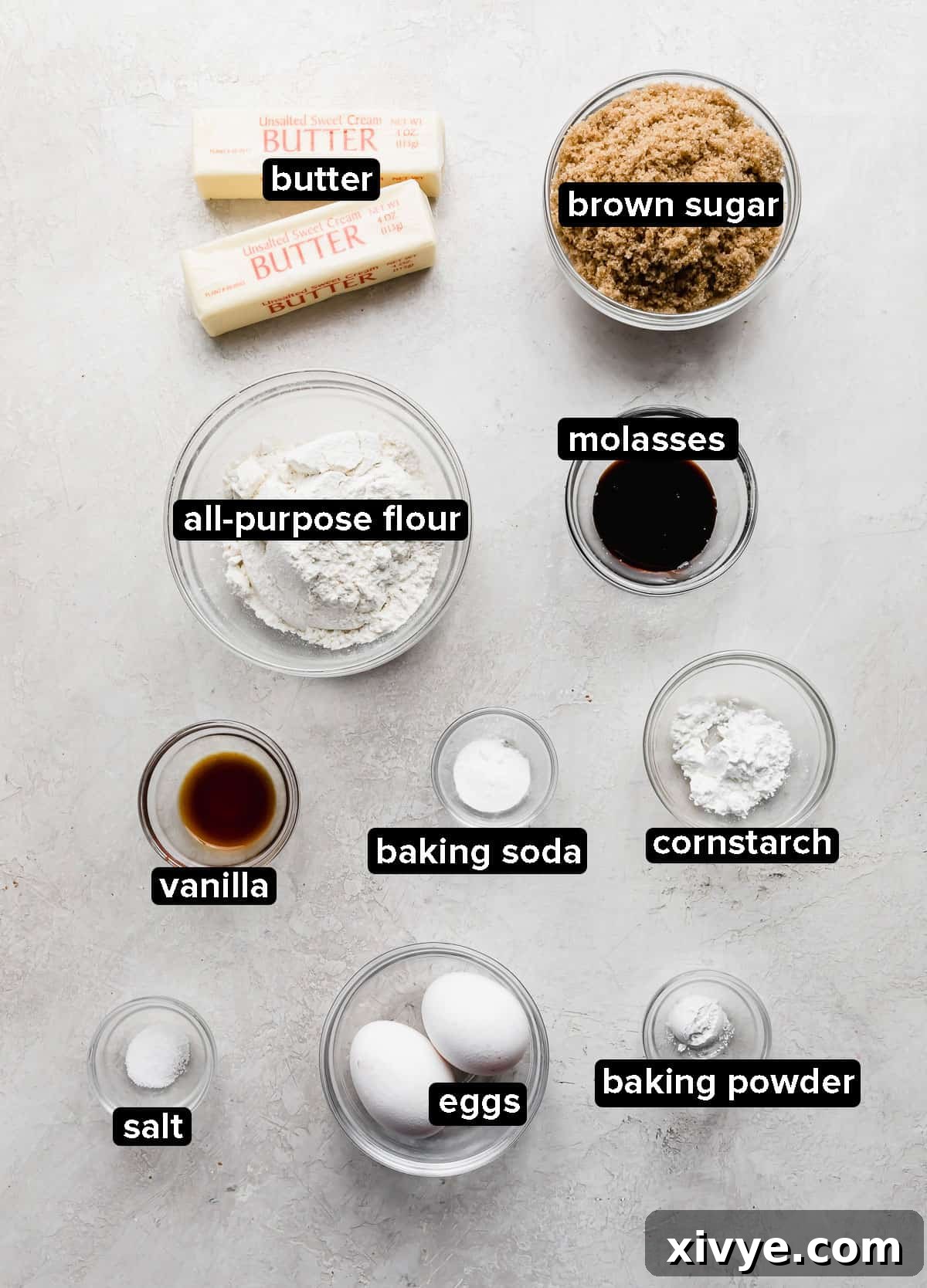 Crumbl Cookie Dough Dream 3 Ingredients in glass bowls such as: flour, butter, sugar, vanilla, salt, baking powder, baking soda, on a gray background.