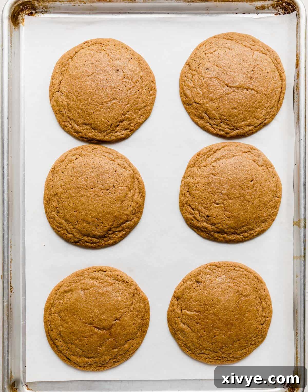 Crumbl Cookie Dough Dream 8 Six brown sugar cookies on a parchment lined baking sheet.