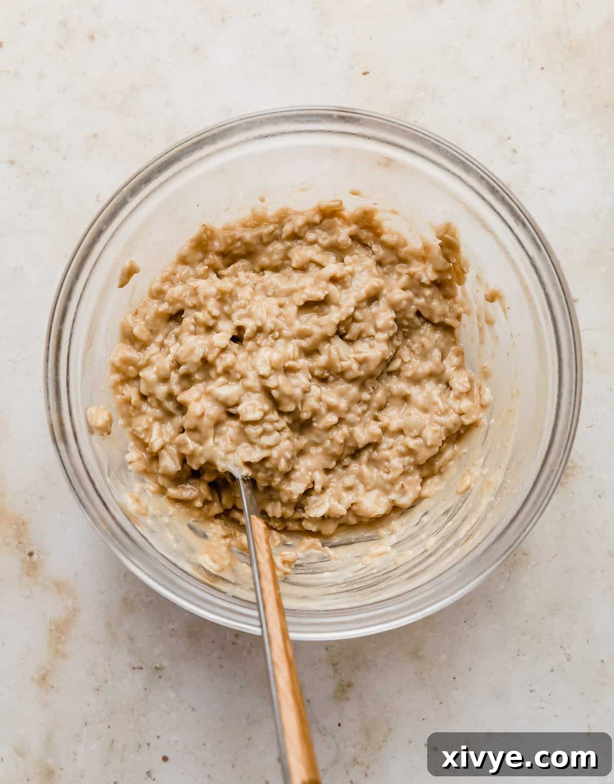 A glass bowl with tan colored peanut butter oatmeal in it.