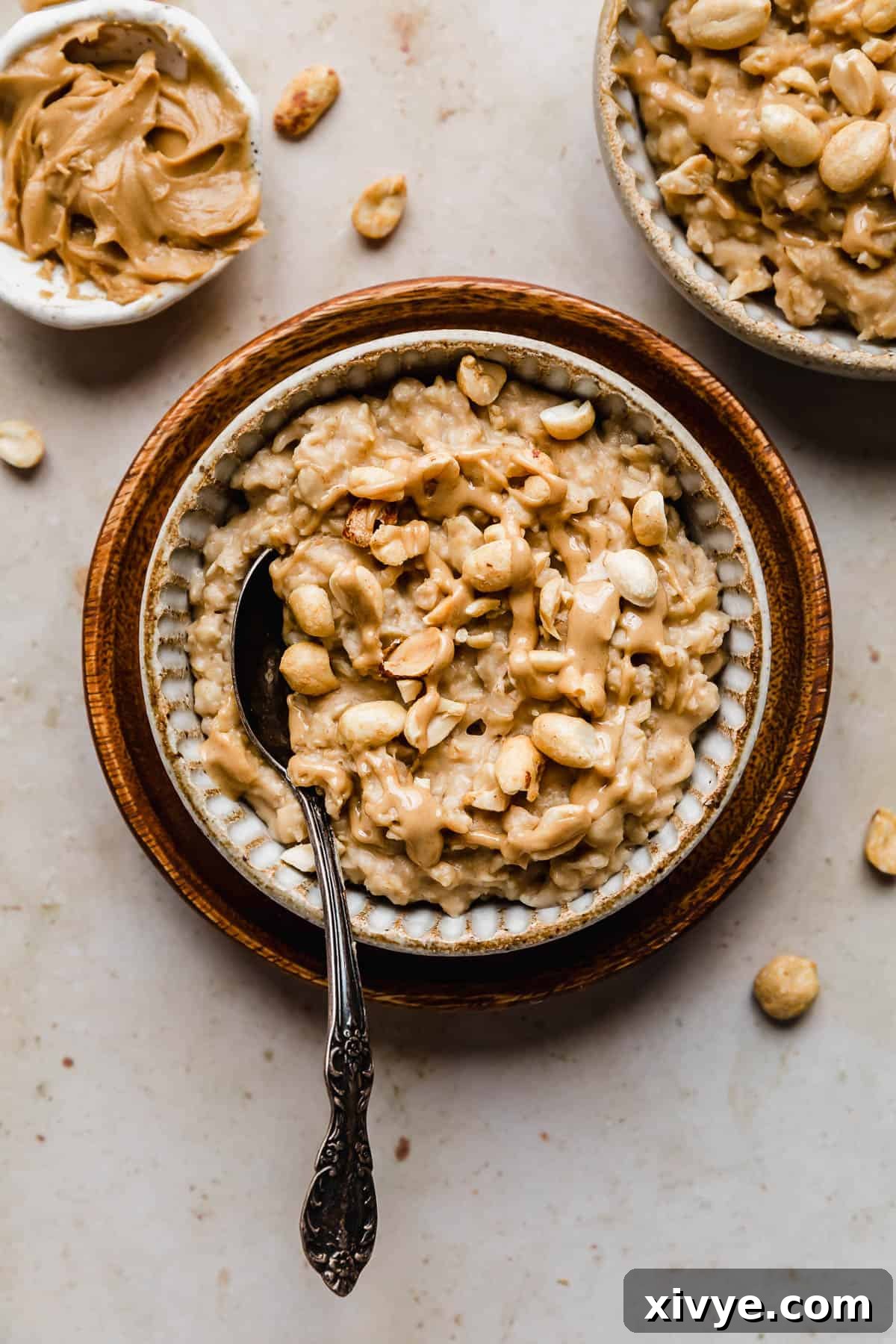 Peanut Butter Oatmeal topped with chopped peanuts in a tan bowl on a brown plate.