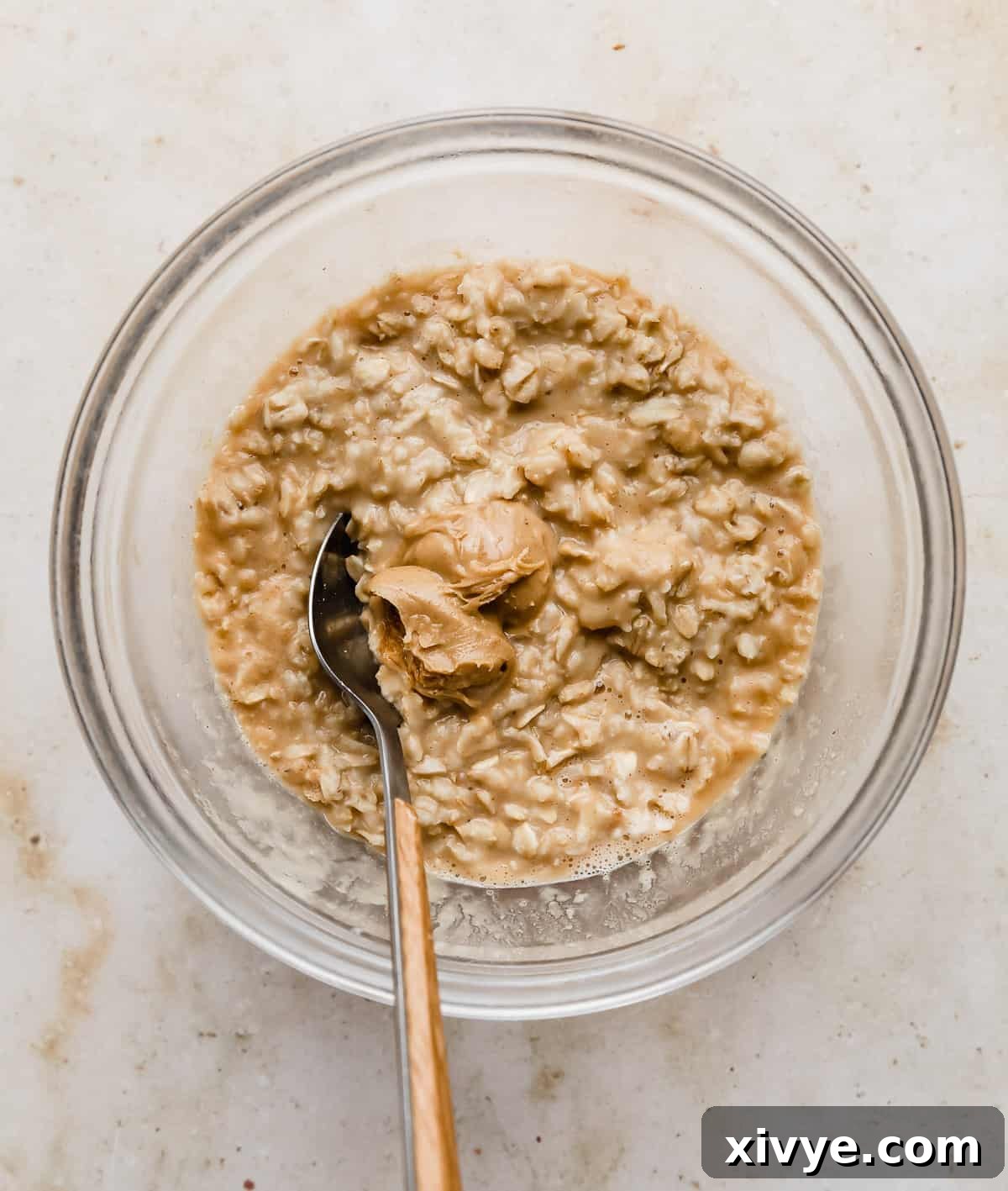 Tan colored oatmeal with a dollop of creamy peanut butter on top.