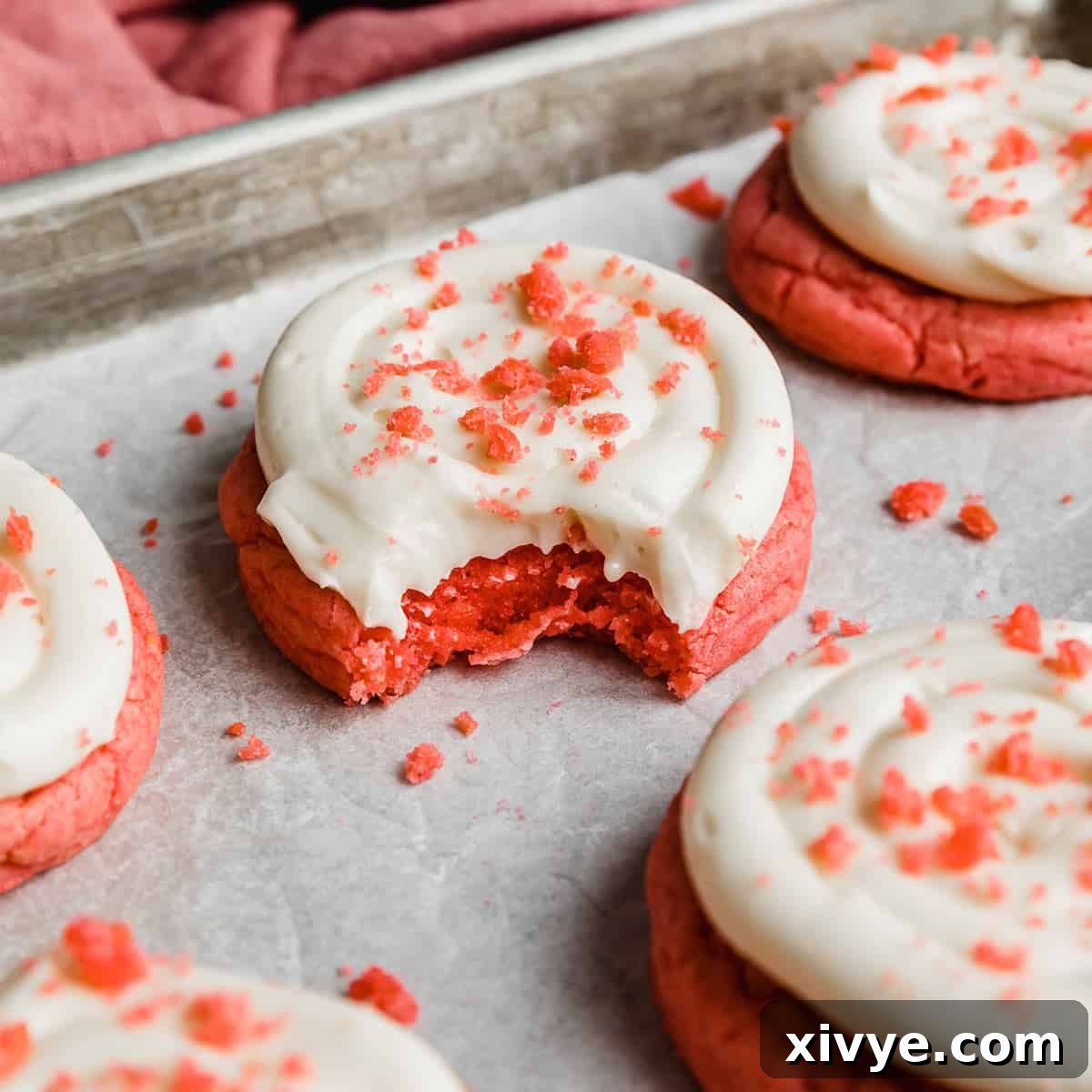 A festive Pink Velvet Cookie adorned with luscious cream cheese frosting and a sprinkle of pink cookie crumbs, showcasing its sweet and vibrant appeal.