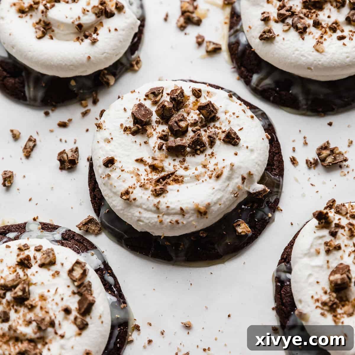 A rich chocolate cookie, a Crumbl copycat, generously topped with caramel, sweetened condensed milk, a swirl of whipped topping, and crunchy Heath toffee bits.