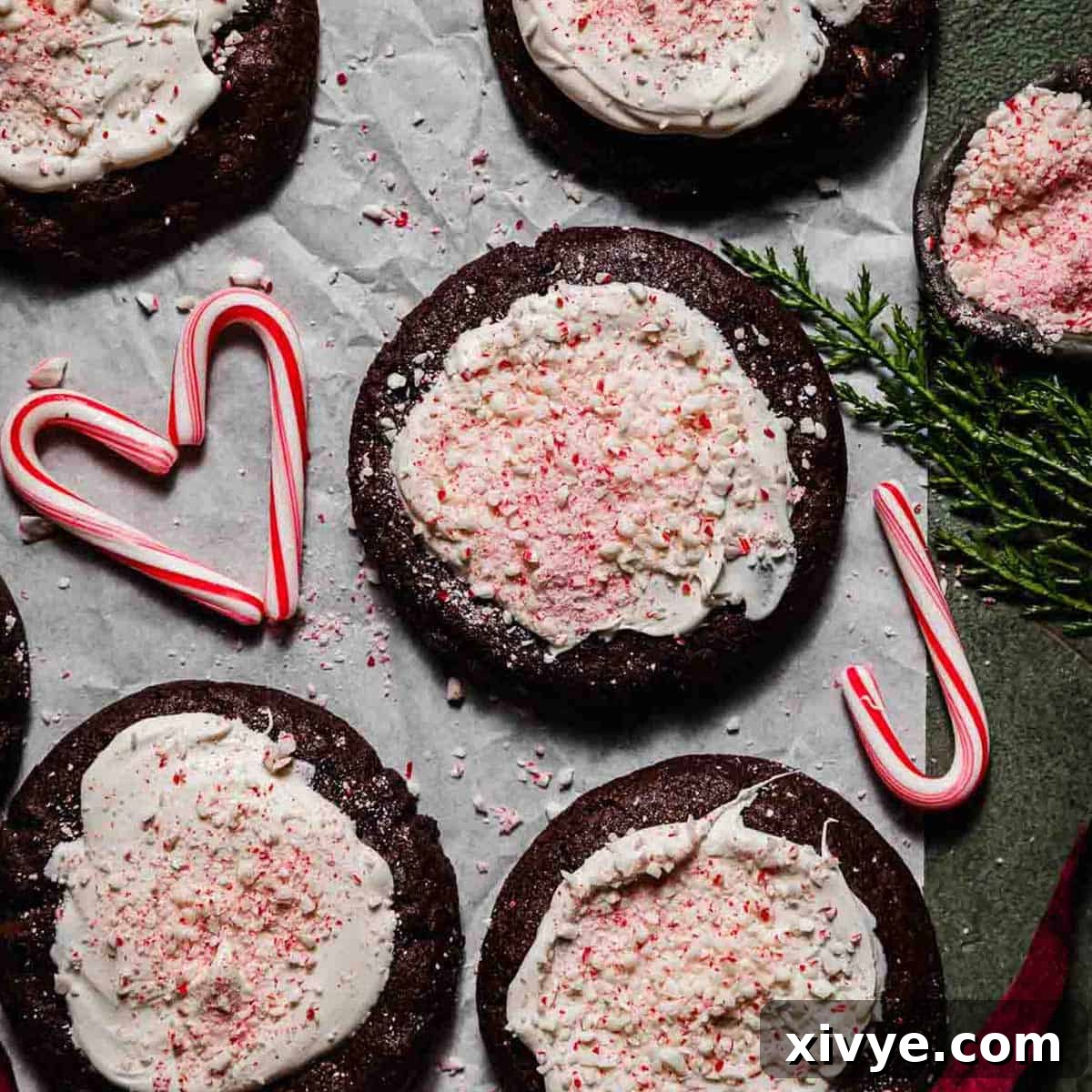 Festive Peppermint Bark Cookies topped with white chocolate and crushed candy canes, on white parchment paper against a forest green background.