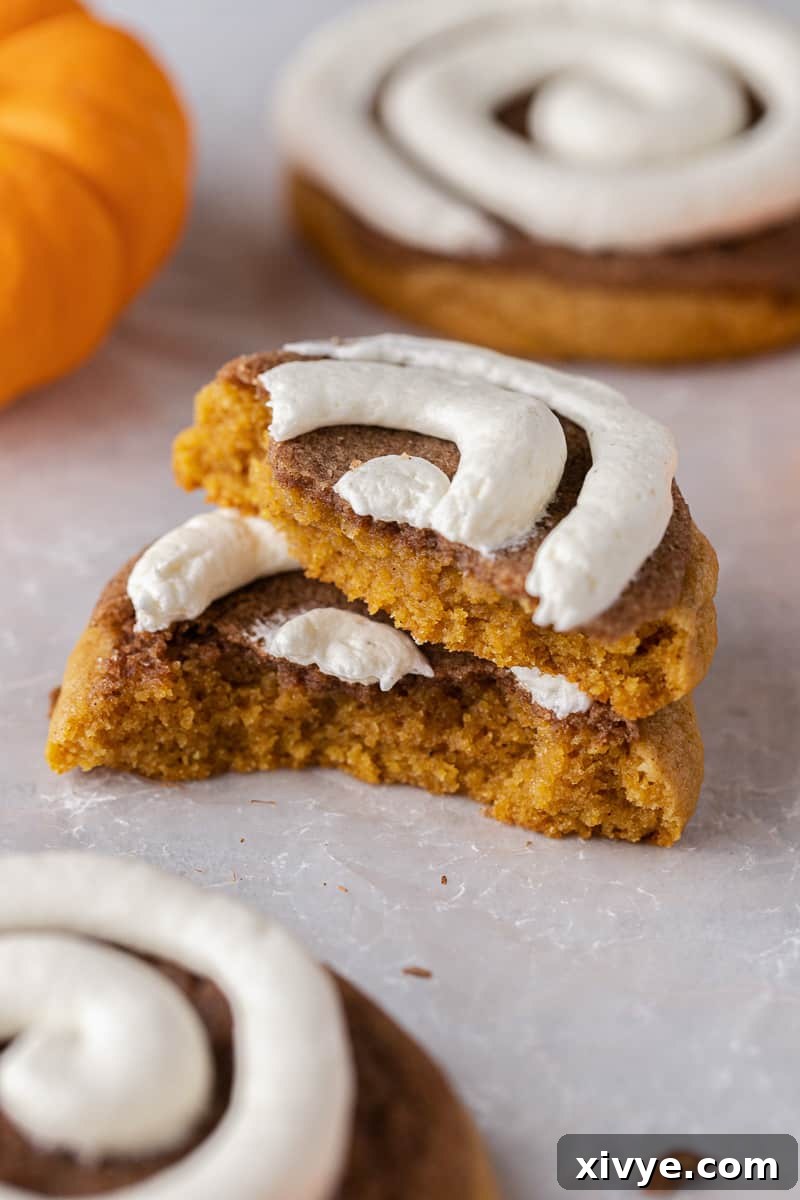 Deliciously chewy Crumbl Pumpkin Roll Cookies, featuring a thick pumpkin cookie base, a dusting of cinnamon sugar, and topped with rich cream cheese frosting.