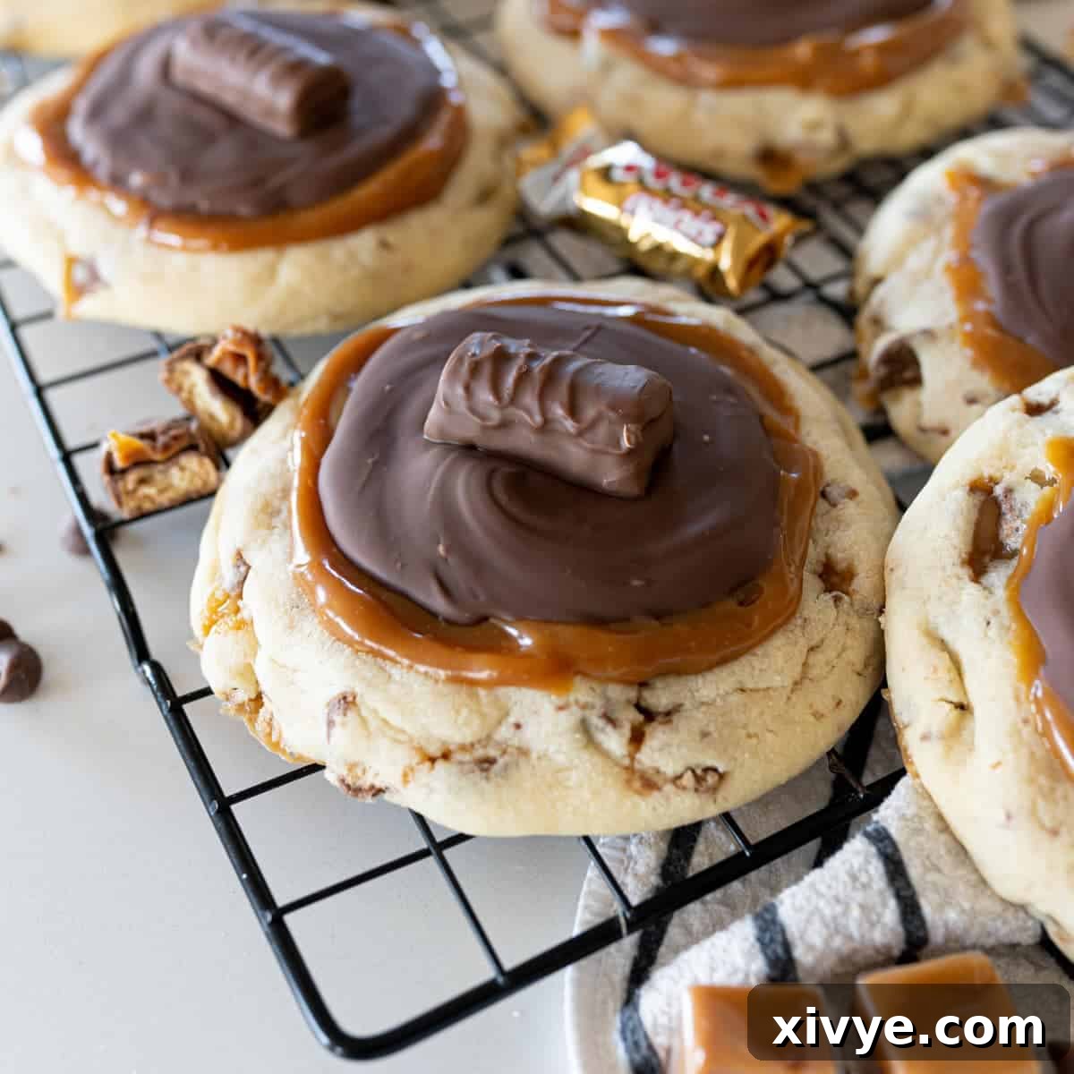 A delicious Copycat Crumbl Twix Cookie, featuring a sugar cookie base studded with Twix pieces, topped with gooey caramel and smooth milk chocolate.