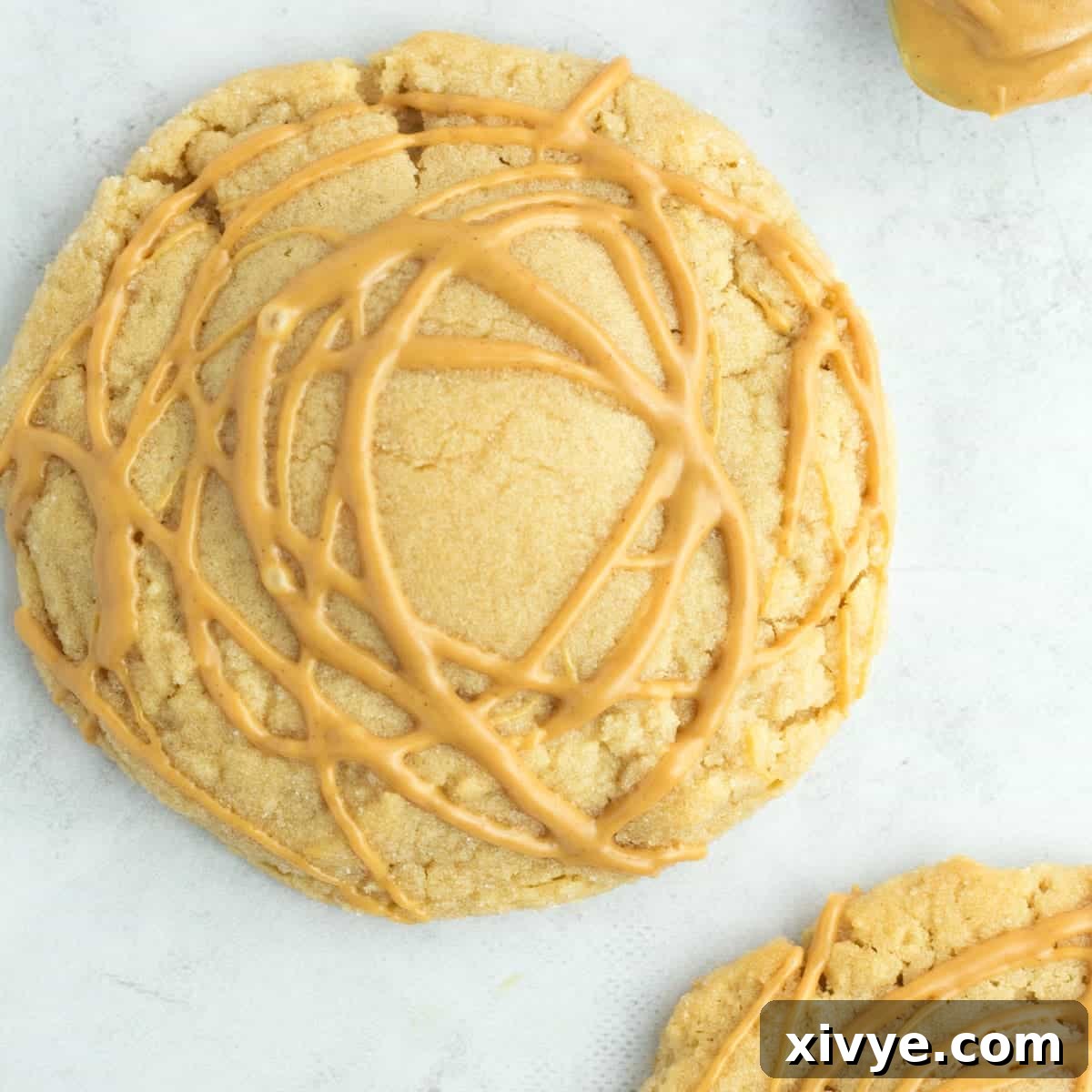 An impressively large and soft Ultimate Crumbl Peanut Butter Cookie Copycat, generously layered with peanut butter and rolled in sugar, showcasing its rich texture.