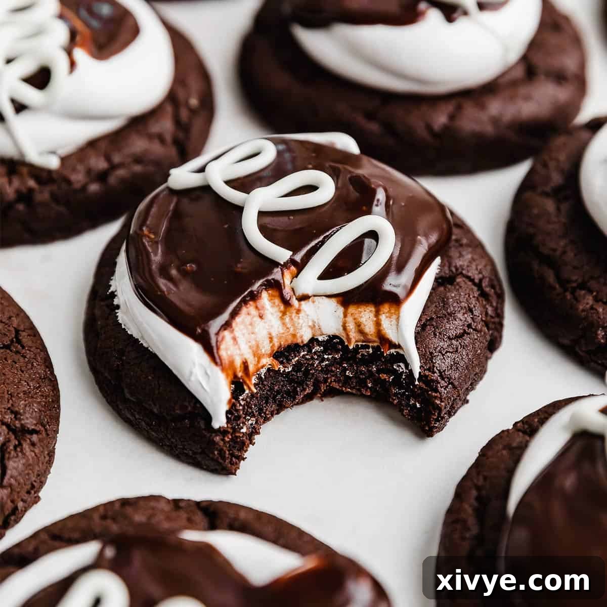 A gourmet Hostess Cupcake Cookie, meticulously decorated with white marshmallow frosting, a swirl of chocolate ganache, and signature white loops, resting on a white table.