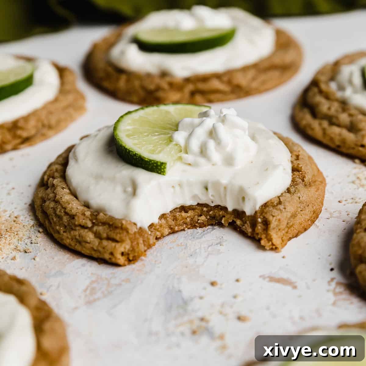 A delectable Key Lime Pie Cookie, showing a bite taken out, featuring a vibrant key lime frosting on a graham cracker base, against a white background.