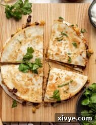 Black Bean and Corn Quesadilla cut into 4 triangles on a wooden cutting board.