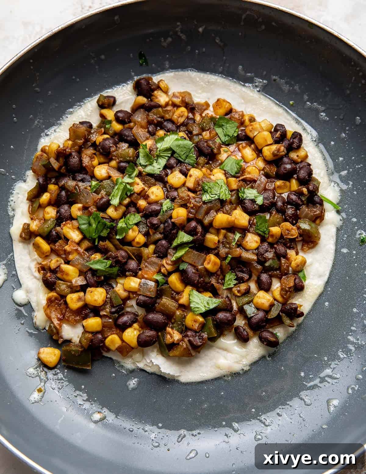 A large flour tortilla generously topped with the savory Black Bean and Corn mixture and cheese, demonstrating the layering process before adding the top tortilla.