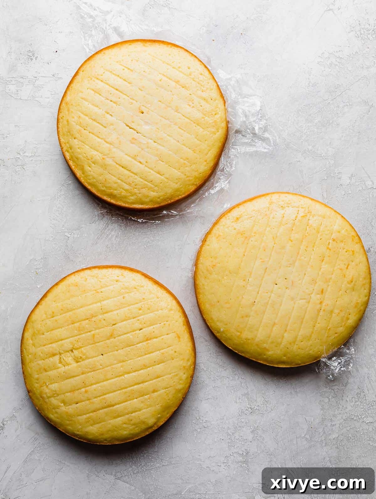 Three perfectly baked orange flavored cake rounds on a gray background, ready for assembly.