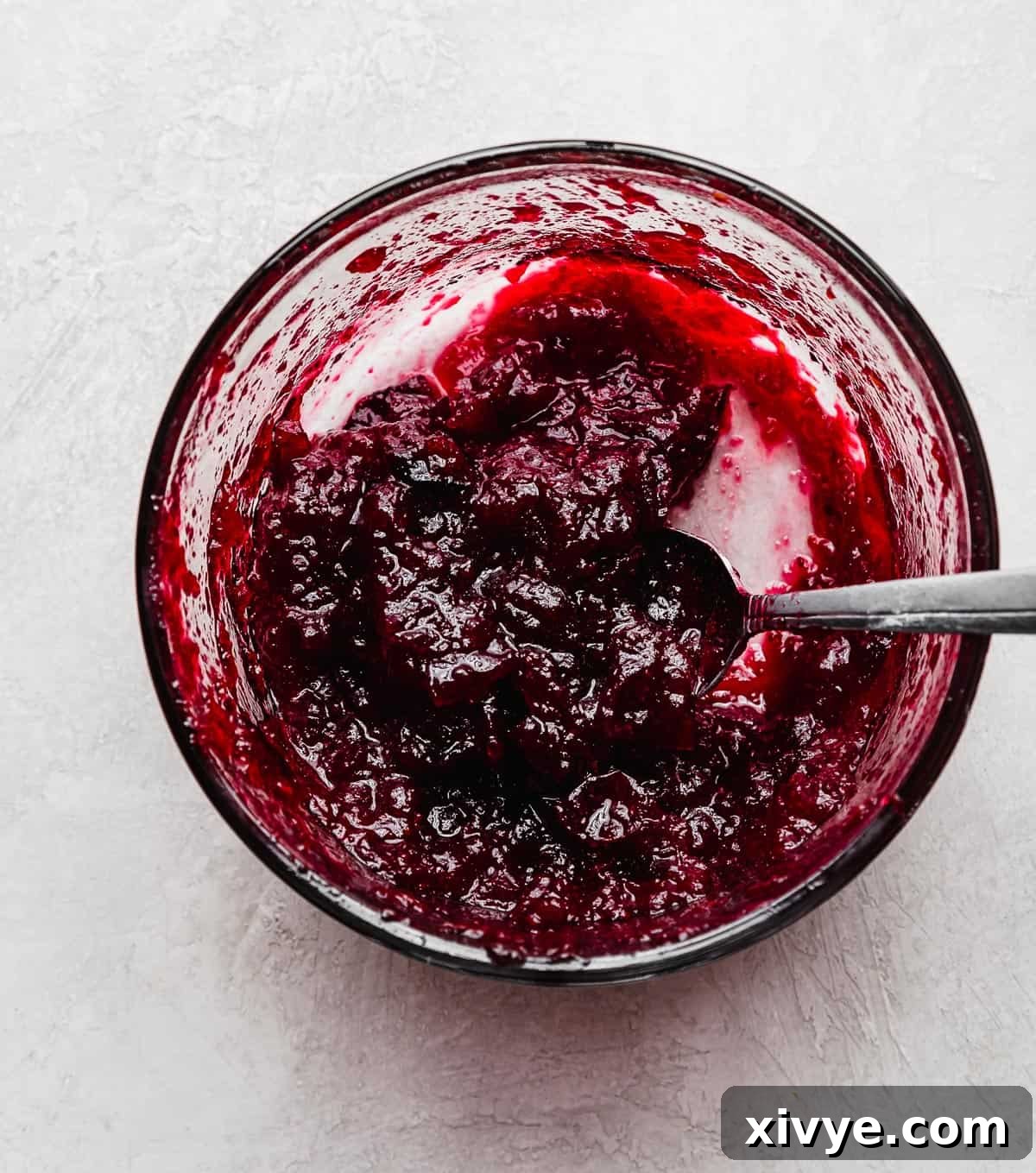 A deep cranberry colored cranberry filling in a glass bowl for an orange cranberry layer cake, ready to be layered.