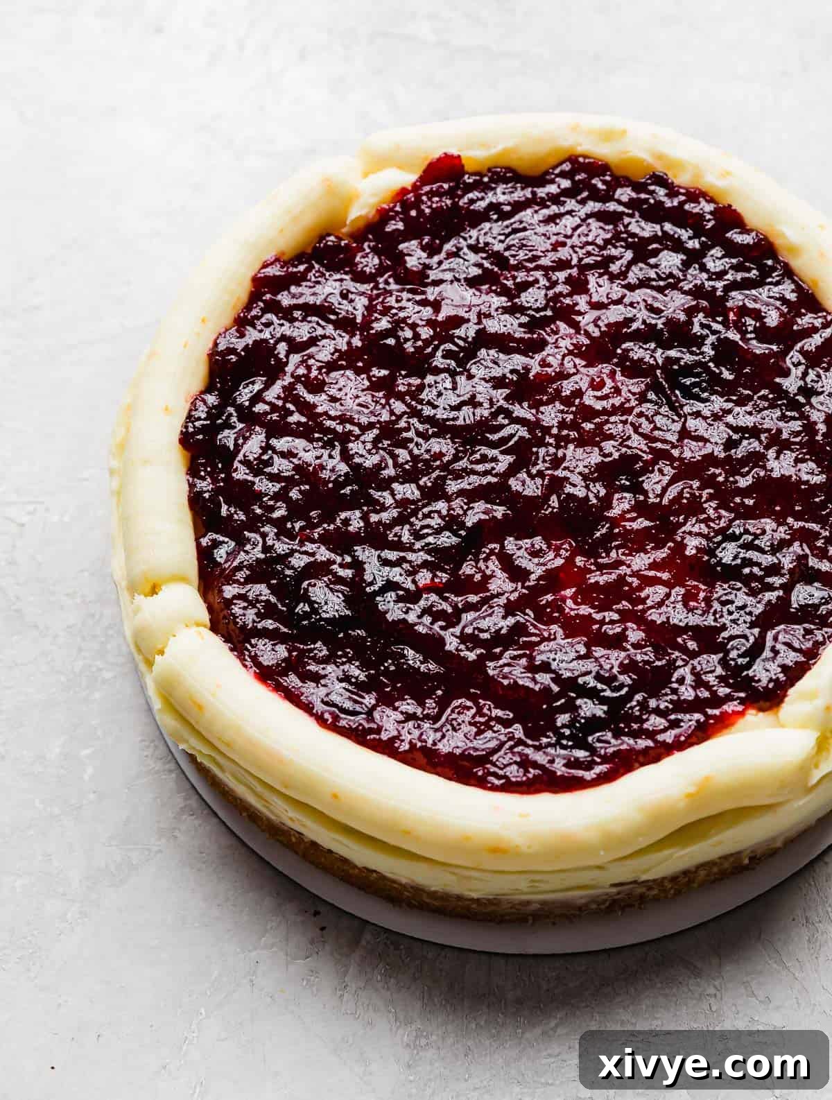 A cake round covered in buttercream with a piped rim around the edges of the cake and cranberry filling in the center, showing the careful layering technique.