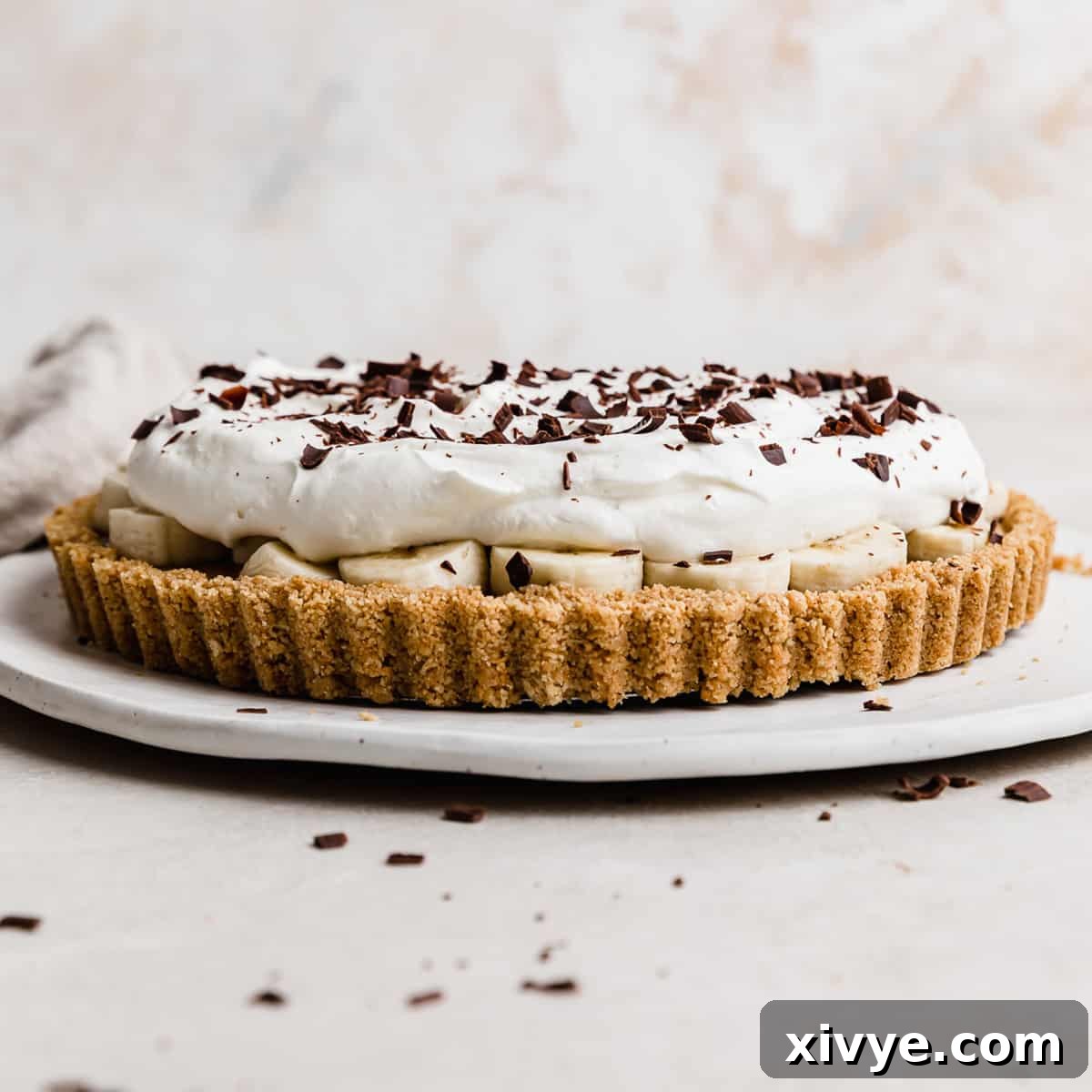 A Banoffee Pie on a white plate, topped with whipped cream and chocolate shavings.