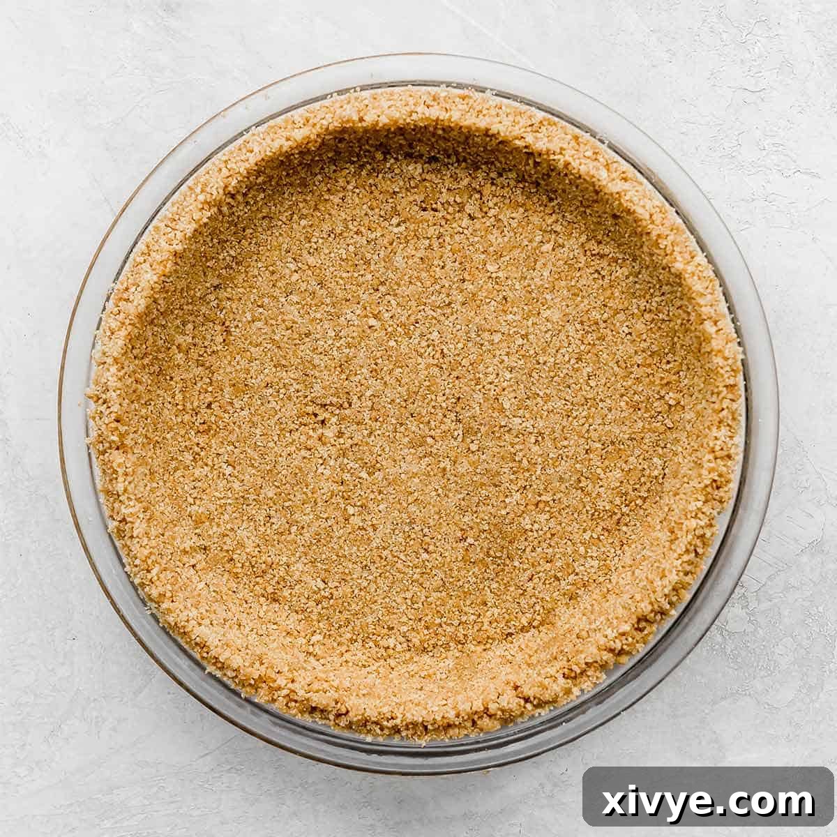 A homemade Graham Cracker Crust pressed into a pie plate on a light gray background.