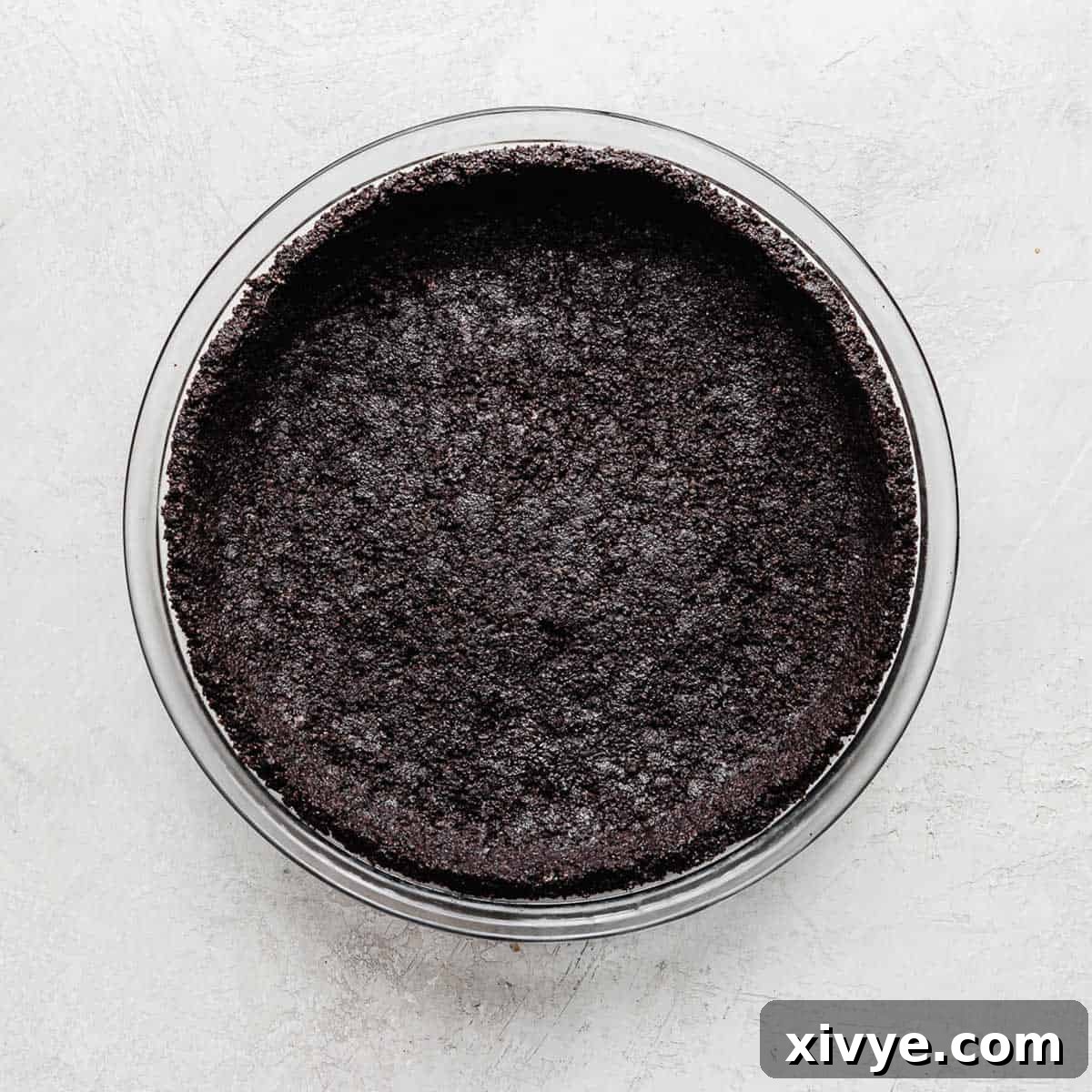 An Oreo Pie Crust in a glass pie dish on a gray background.