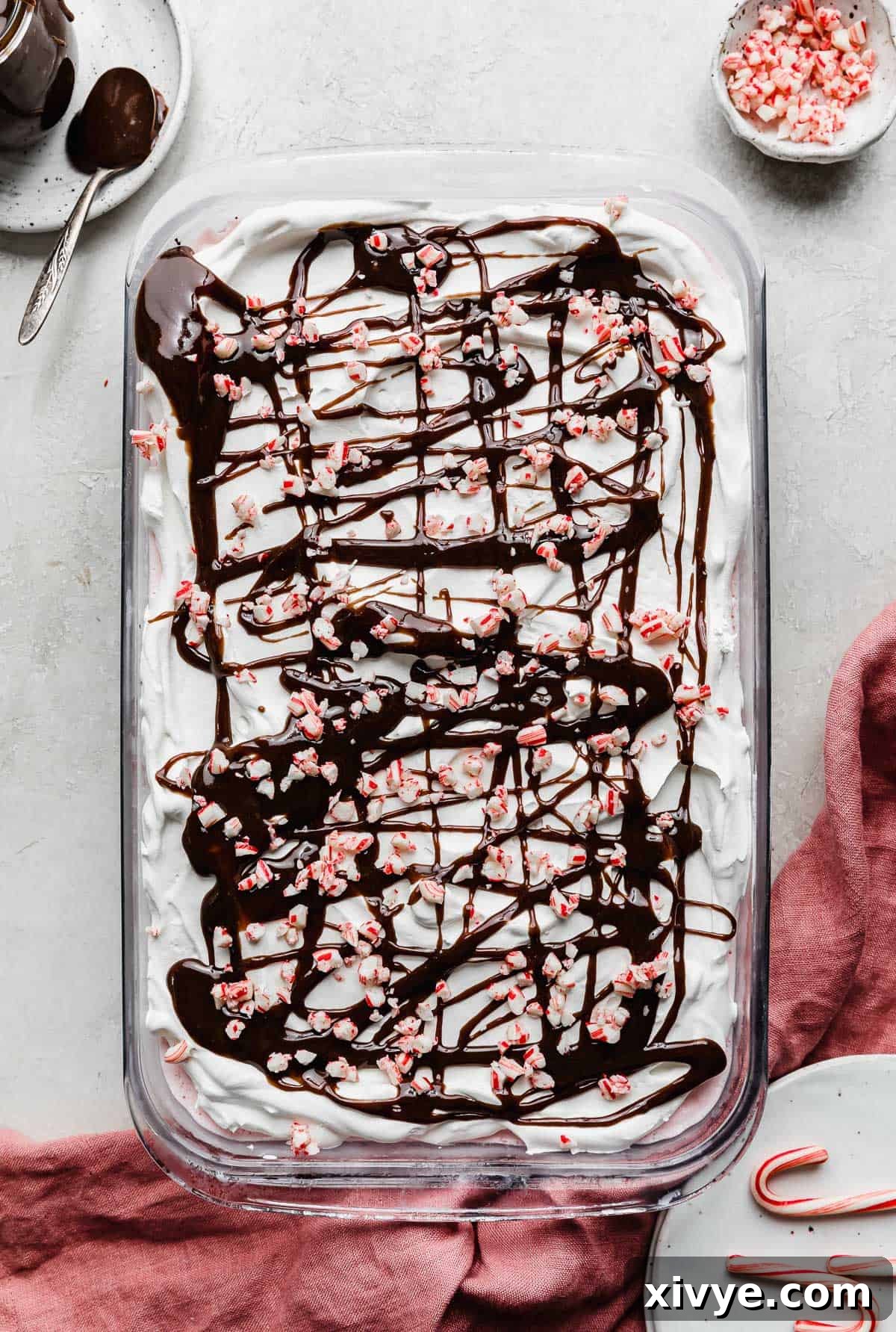The fully decorated peppermint Christmas Ice Cream Cake, generously topped with hot fudge swirls and vibrant crushed candy canes.
