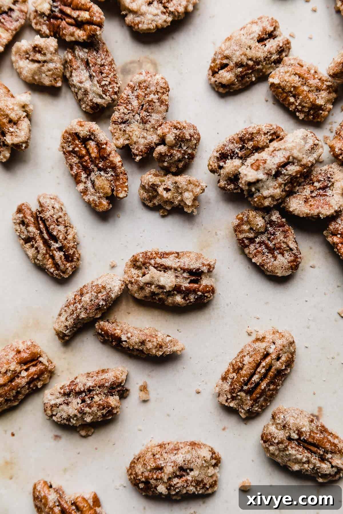 Sweet Glazed Pecans 11 Perfectly roasted candied pecans cooling on a tan background, showcasing their golden-brown color and crunchy texture.