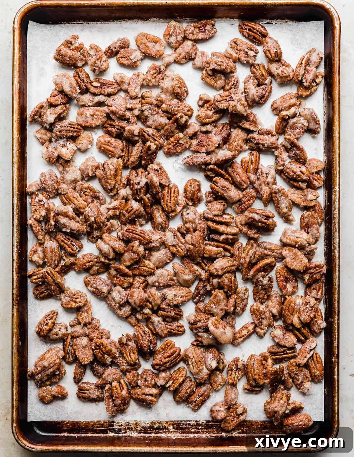 Sweet Glazed Pecans 9 Freshly coated candied pecans spread out on a baking sheet, ready for roasting in the oven.