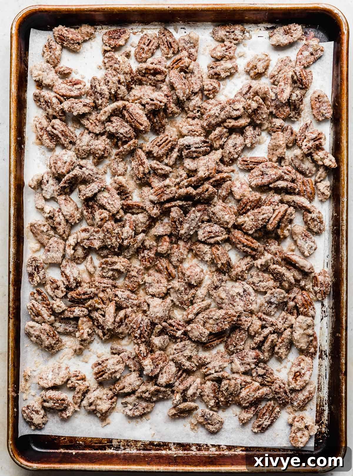 Sweet Glazed Pecans 10 A baking sheet uniformly covered with a single layer of cinnamon-sugar coated pecans, illustrating proper spacing for even baking.
