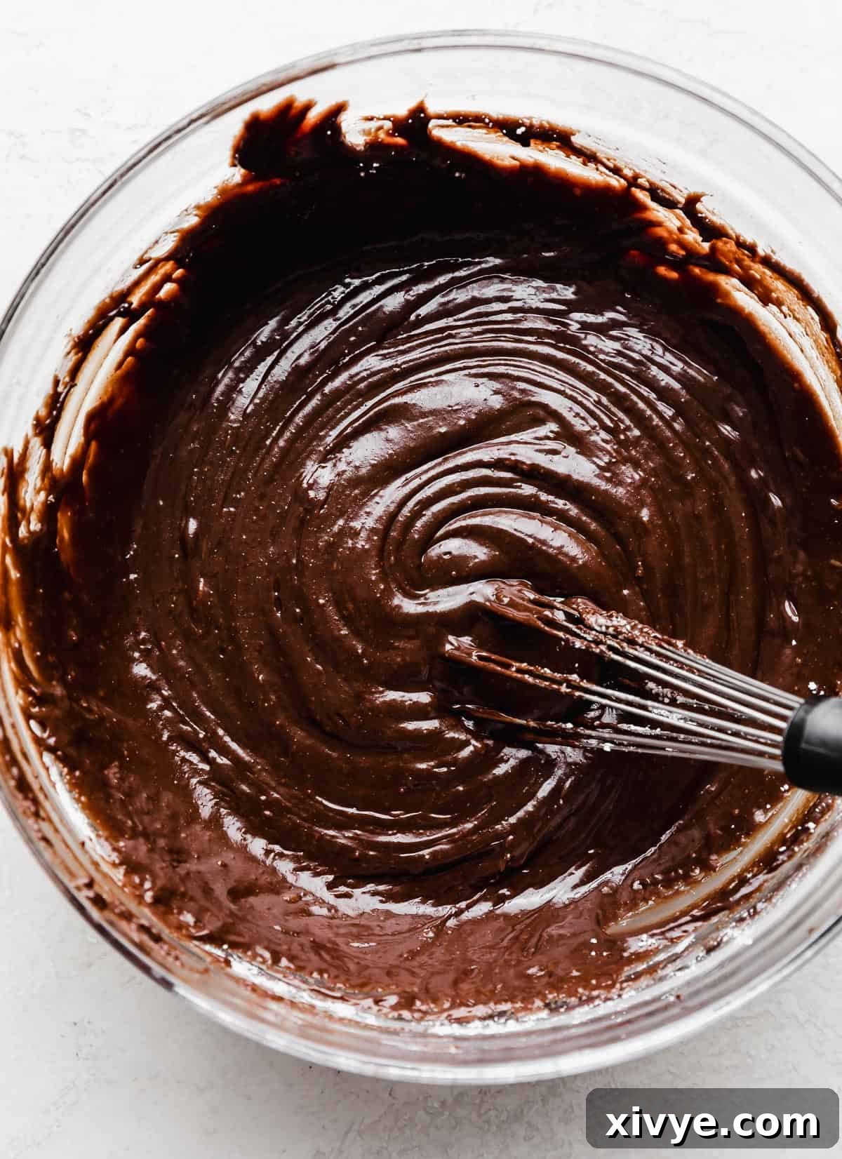 A thick chocolate Bundt Cake frosting in a glass bowl.