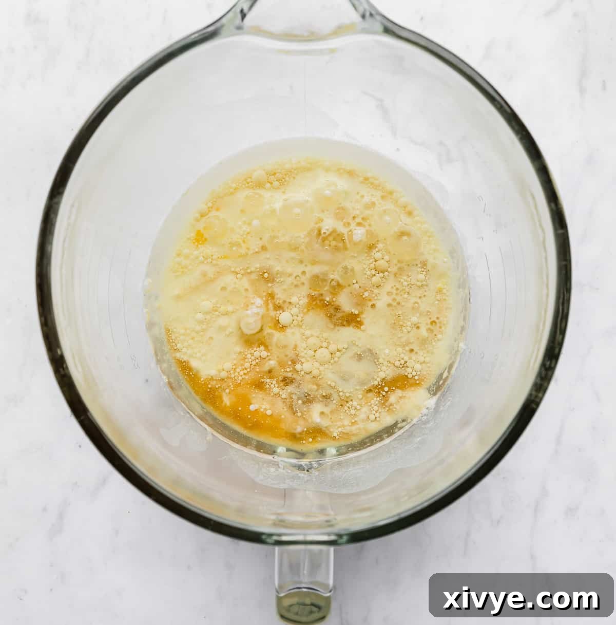 A glass mixing bowl with oil, eggs, buttermilk, and vanilla in it.