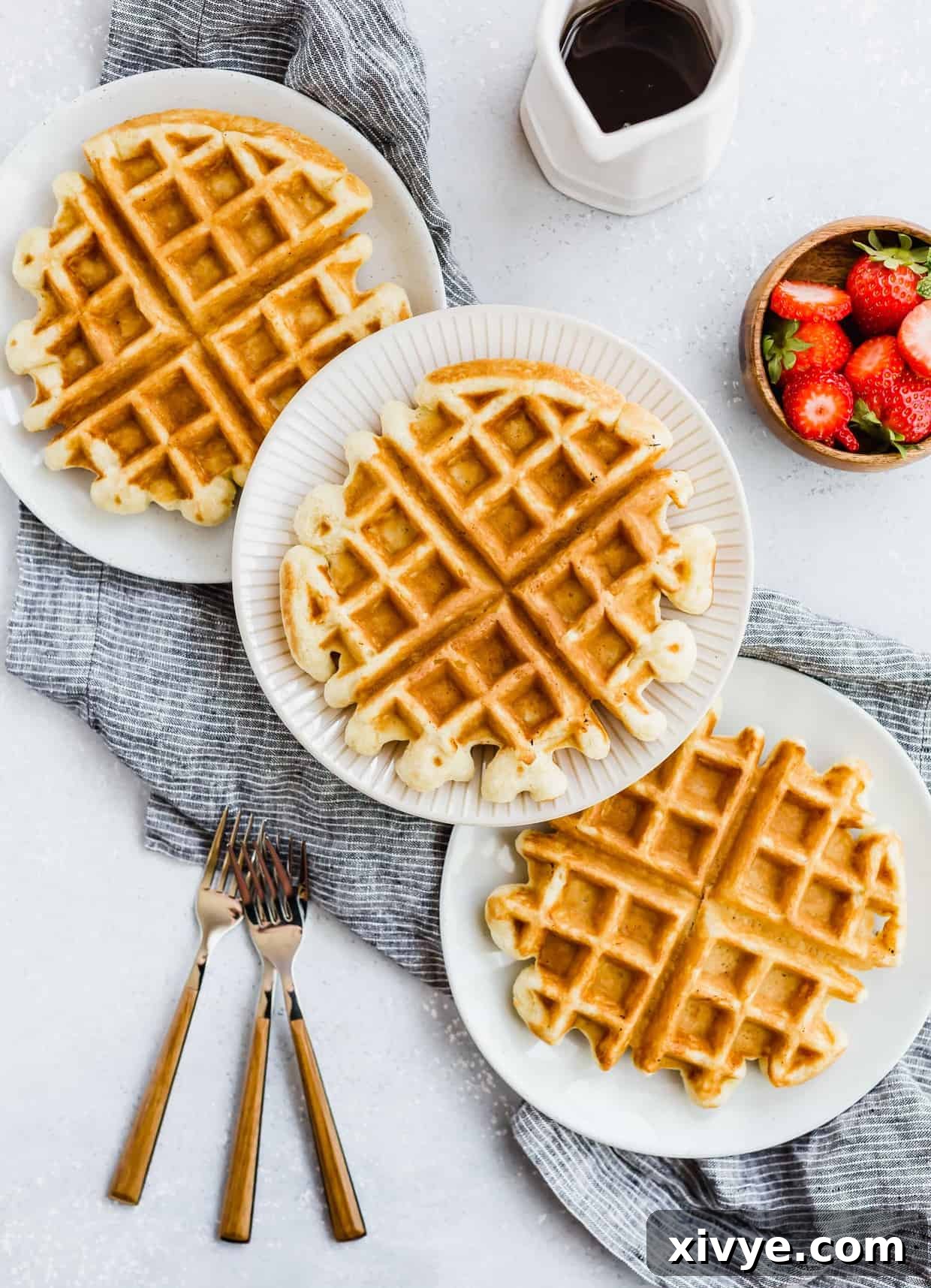 Three buttermilk waffles with three forks to the side.