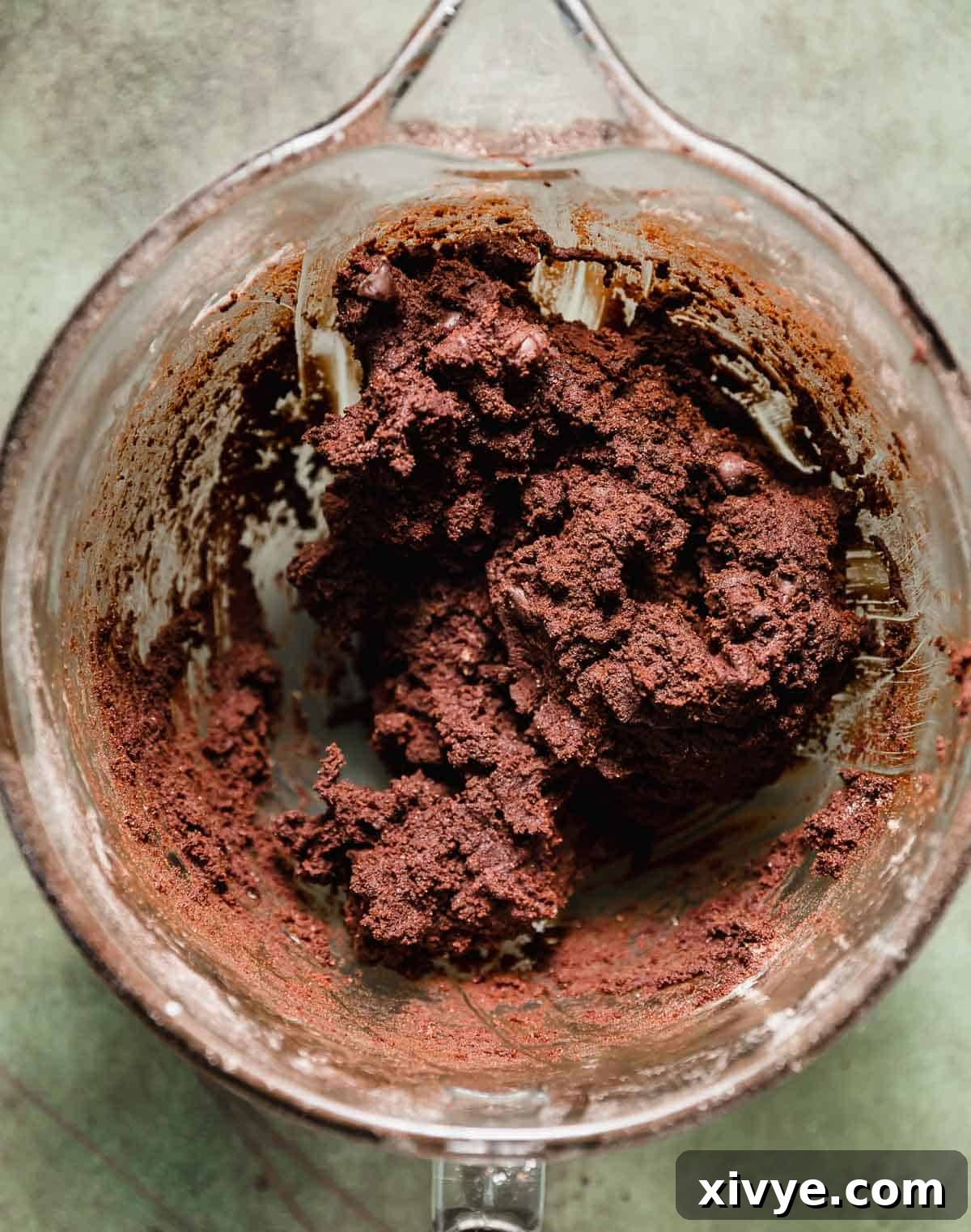 Peppermint Bark Bites 4 A chocolate cookie dough in a glass mixing bowl on a green background.