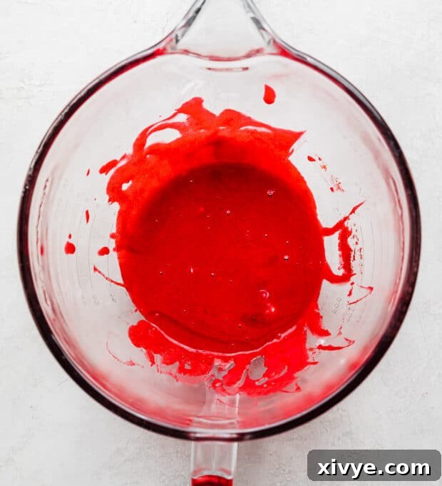 Velvet Dream Doughnuts 4 A vibrant red colored wet ingredients batter, smooth and well-combined, resting in a clear glass bowl, ready for the next step.