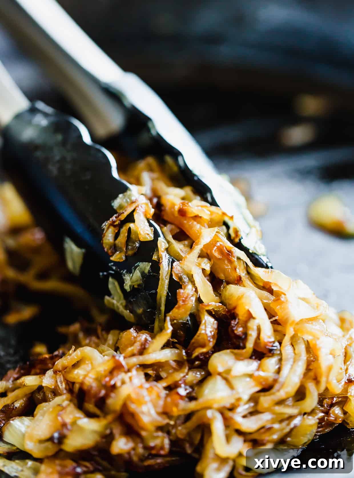 Velvety Onion Cream Cheese Dip 5 Fully caramelized onions with tongs grasping some of the onions.