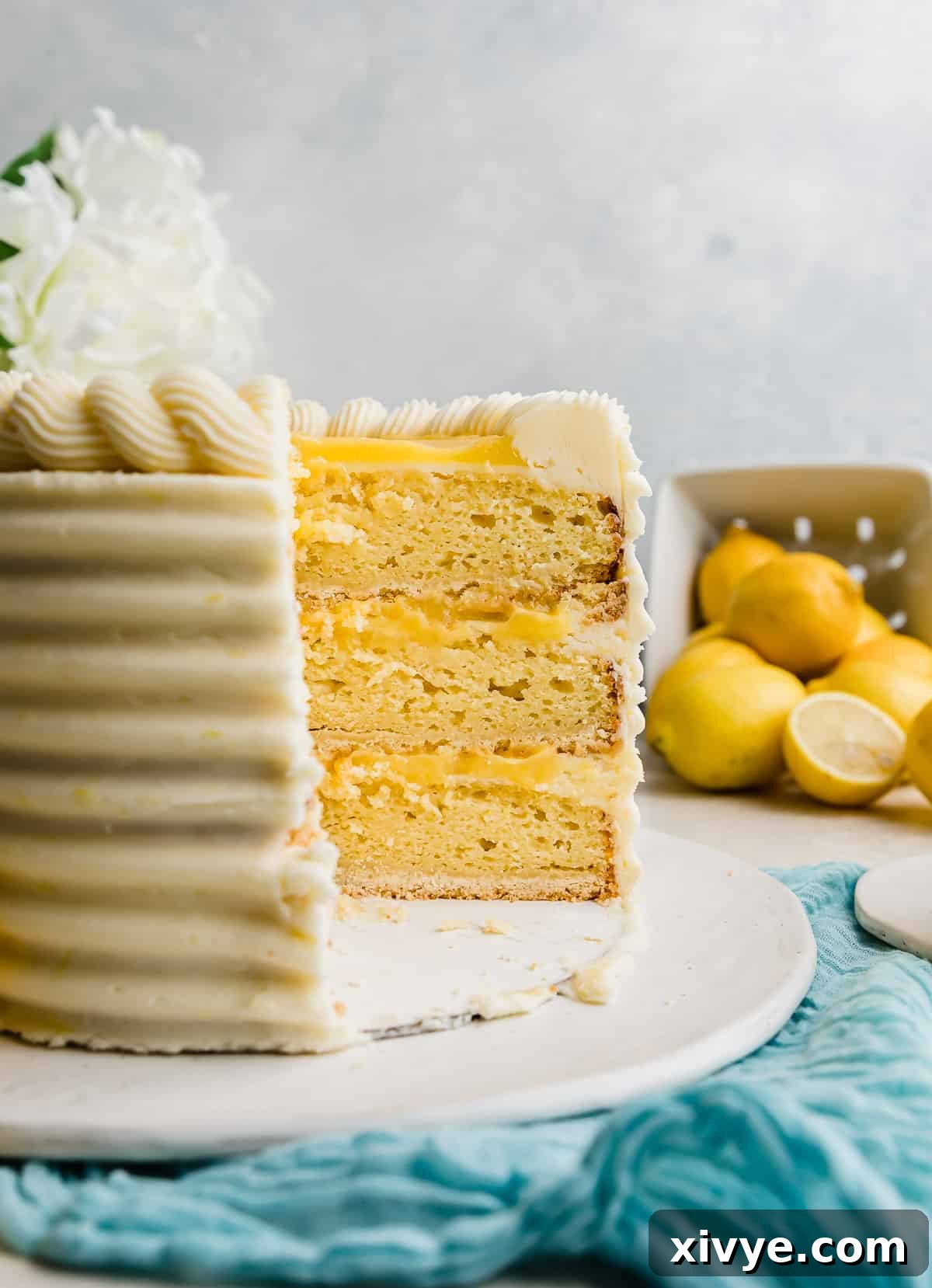 A slice of Lemon Bar Cake, revealing the perfectly layered shortbread crust, moist lemon cake, tart lemon curd, and fluffy lemon frosting.