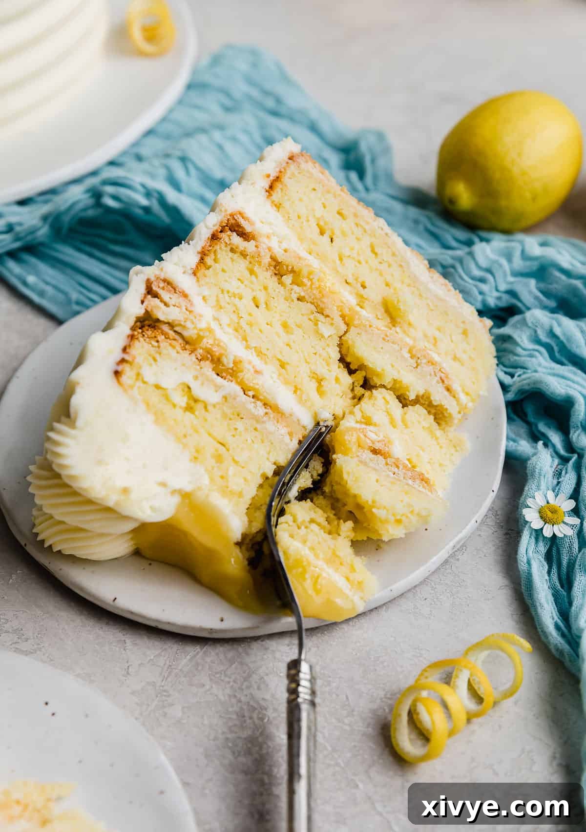 A delicious slice of layered Lemon Bar Cake on a plate, with a fork cutting into its inviting layers.