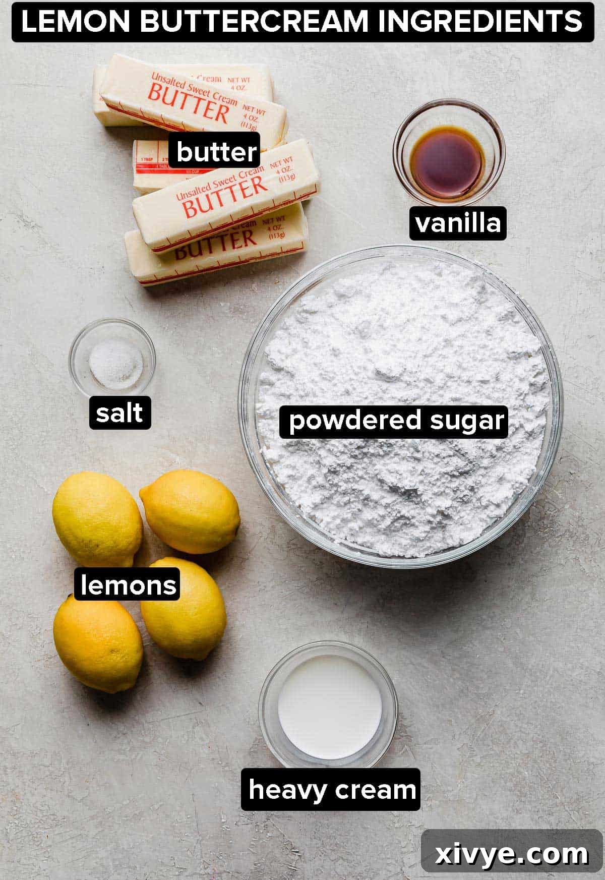 Lemon buttercream ingredients on a light grey background, featuring butter, powdered sugar, lemons, and heavy cream.