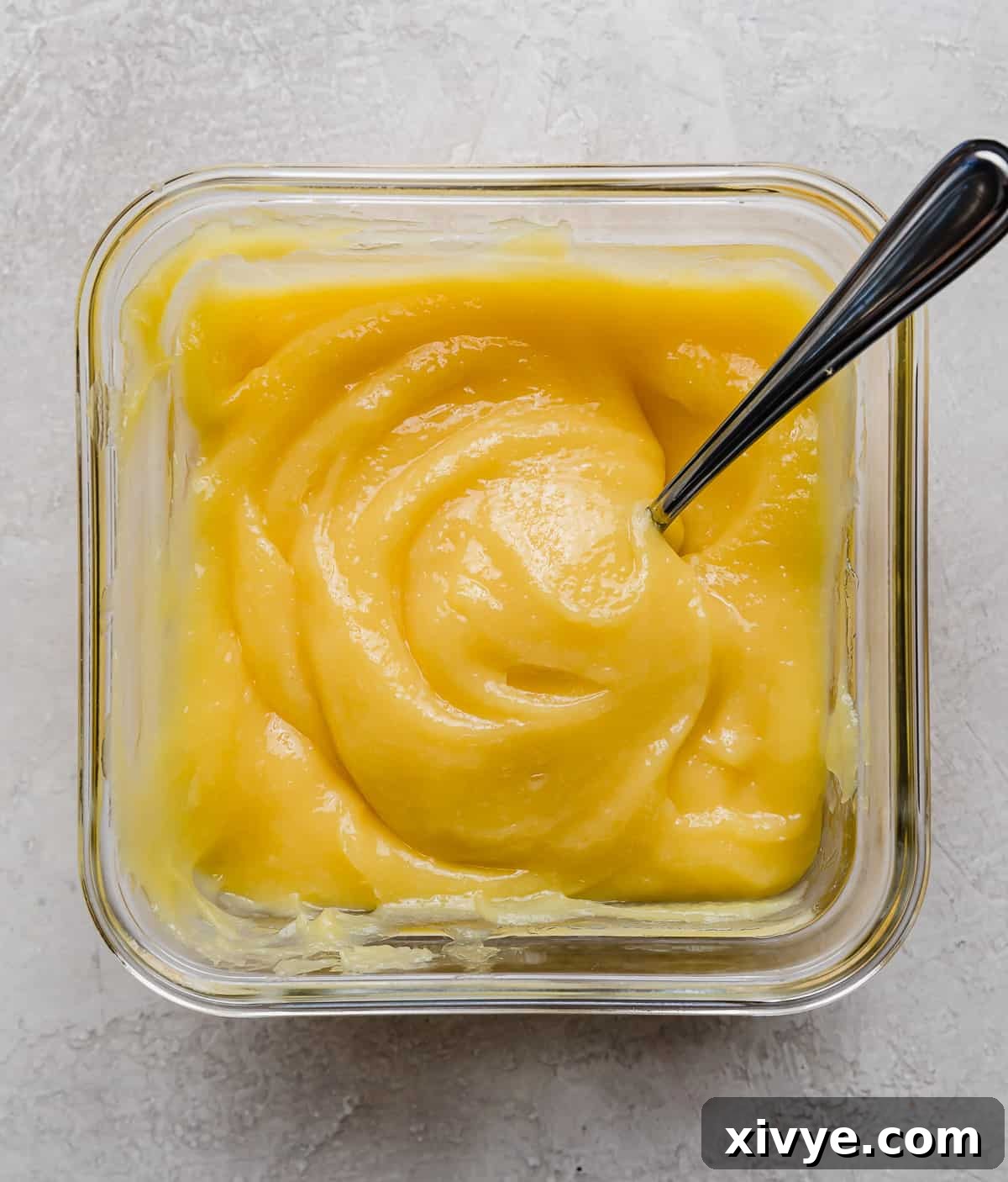 Vibrant yellow lemon curd in a square glass dish, perfectly set and smooth.