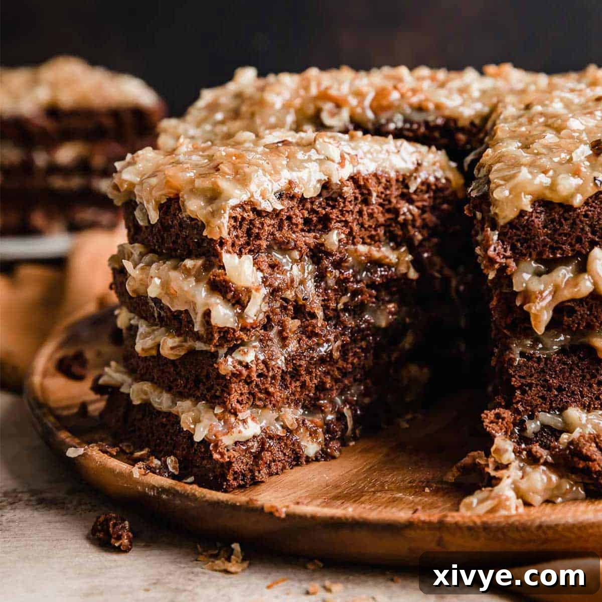 An enticing slice of Traditional German Chocolate Cake, revealing its moist chocolate layers and rich coconut pecan frosting, taken from a grand four-layer cake.