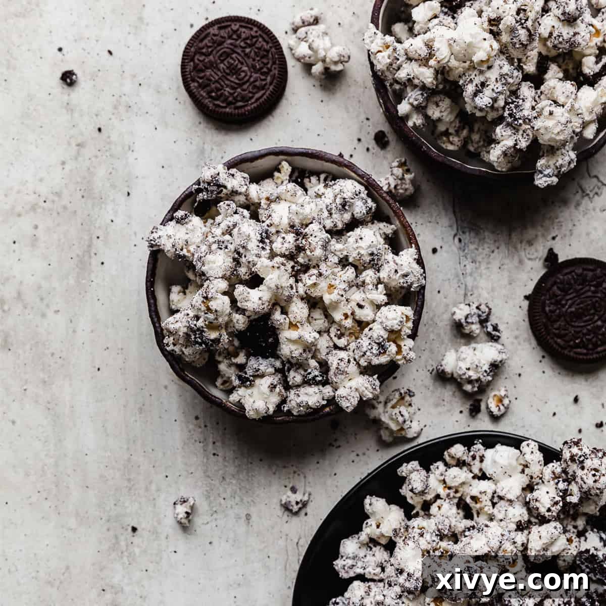 Irresistible Oreo Creations 14 A tantalizing black bowl filled with Oreo crumbs and white chocolate covered popcorn, artfully placed on a gray textured background, ready for snacking.