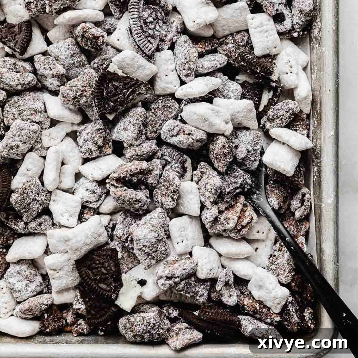 Irresistible Oreo Creations 15 A generous serving of Oreo Muddy Buddies, delightfully tossed with chopped Oreos and powdered sugar, spread out on a baking sheet.