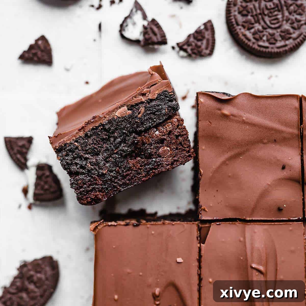 Irresistible Oreo Creations 18 A perfectly cut Oreo Truffle Brownie, showcasing its rich layers of fudgy brownie, creamy Oreo truffle, and glossy chocolate ganache, on a white background.