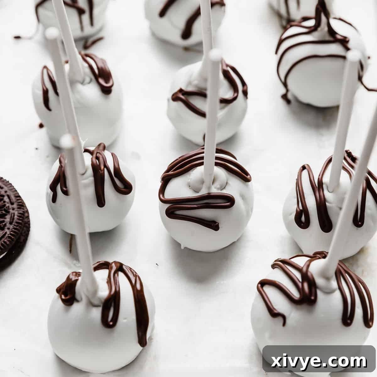 Irresistible Oreo Creations 8 An array of white chocolate covered Oreo Pops, elegantly drizzled with brown chocolate, showcasing their perfect round shape.
