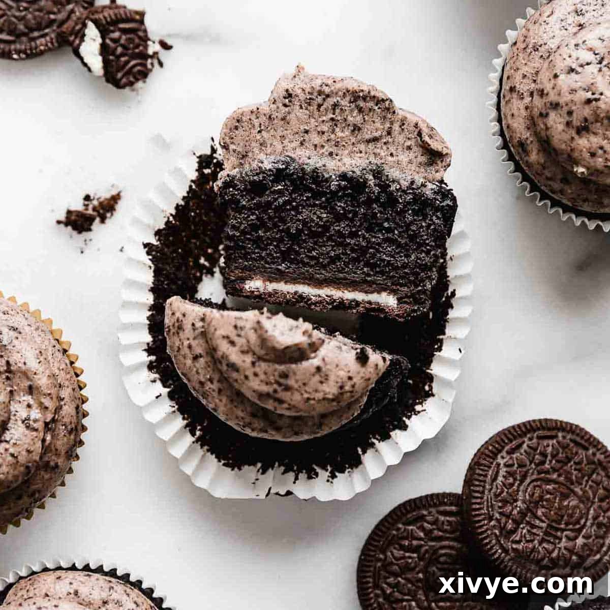 Irresistible Oreo Creations 10 An exquisitely decorated Oreo Cupcake, topped with a generous swirl of Oreo frosting, cleverly cut in half to reveal a whole Oreo cookie nestled at its base.