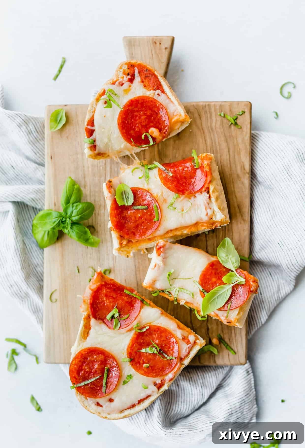 An overhead view of a French Bread Pizza generously topped with savory pepperoni and elegantly garnished with fresh basil leaves.