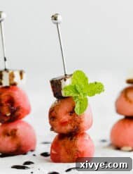 Three Watermelon Feta Skewers with balsamic reduction overtop.
