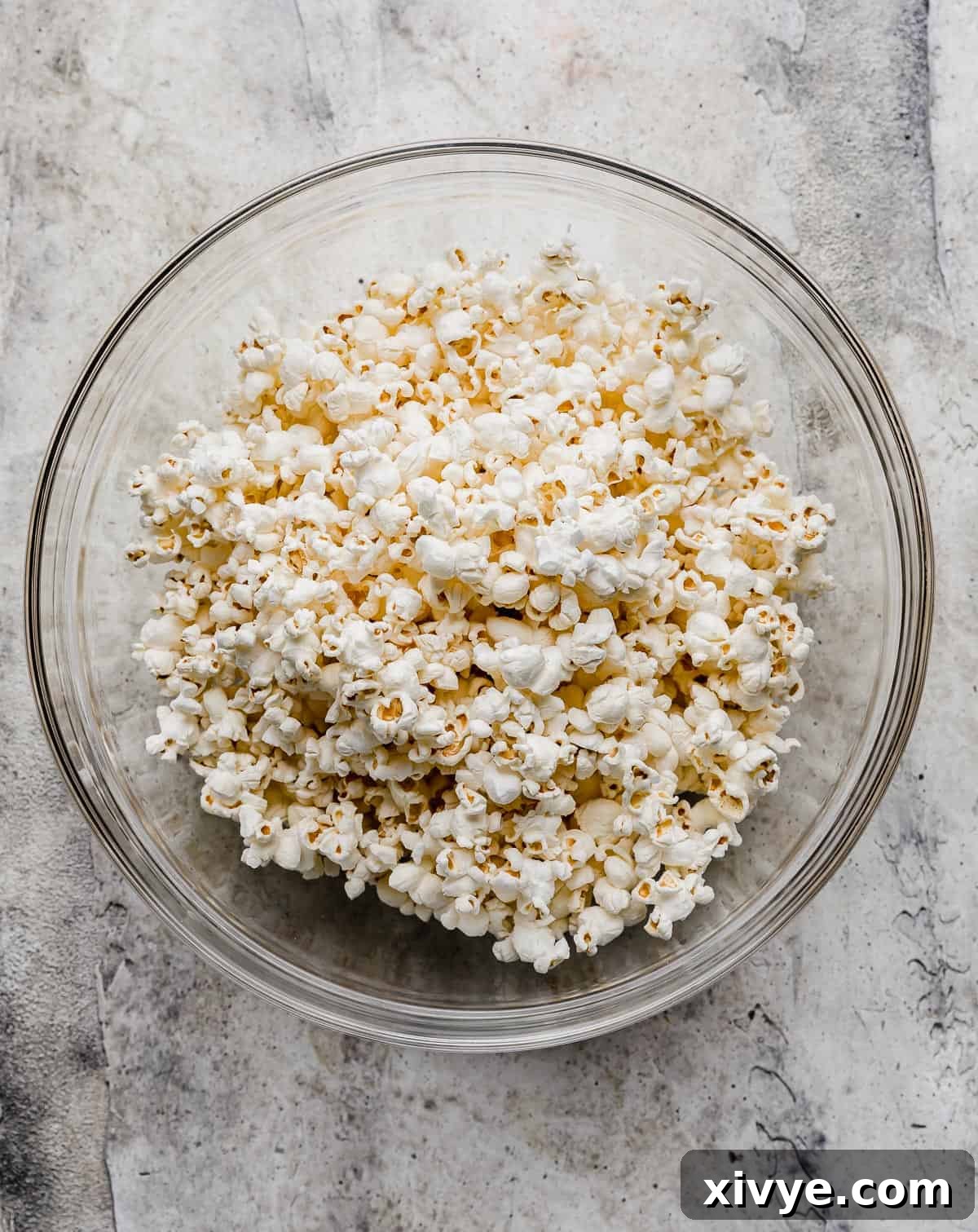 Freshly popped popcorn ready in a large glass bowl for coating.