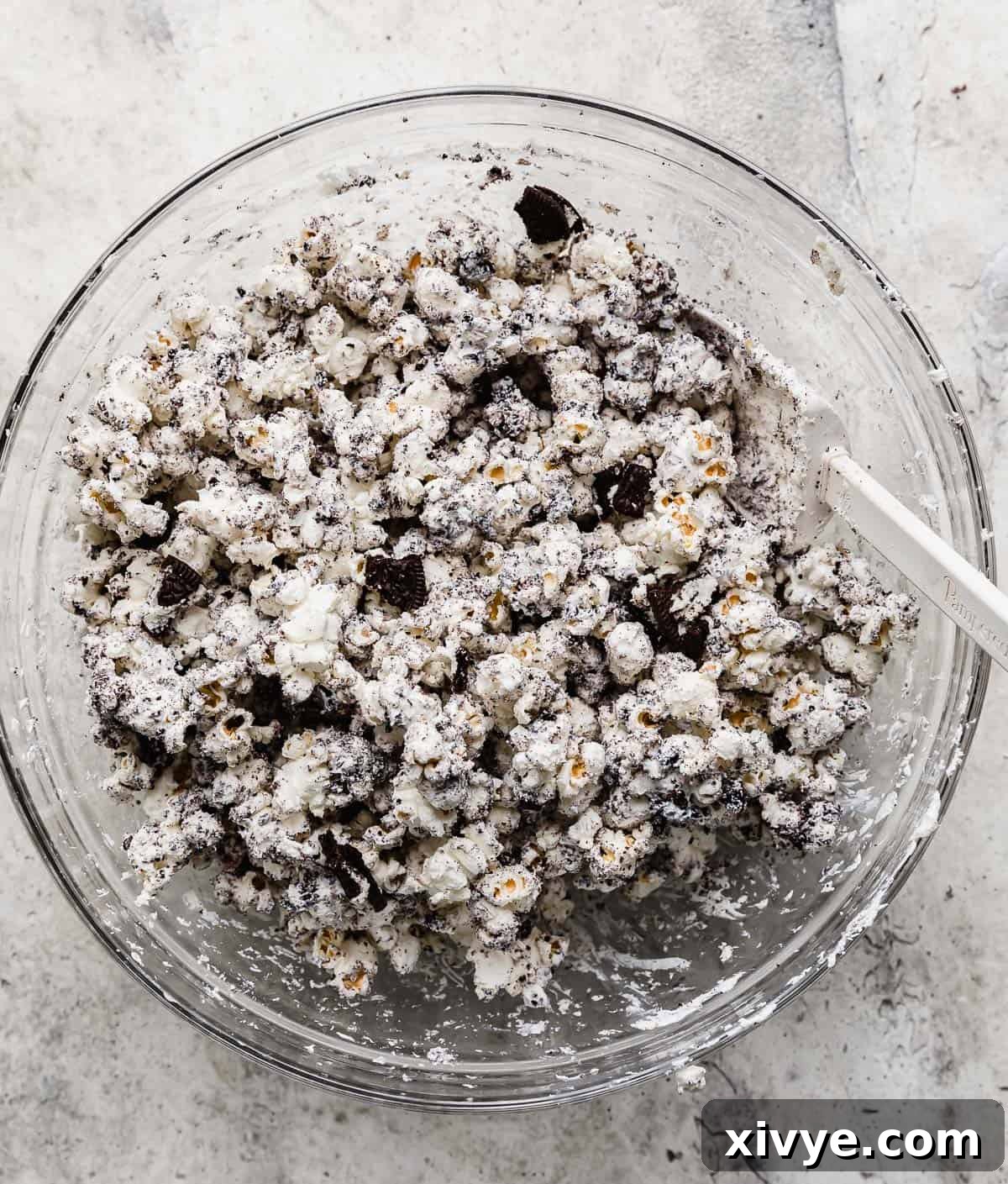A large glass bowl filled with cookies and cream-style Oreo Popcorn, showcasing generous amounts of white chocolate and crushed cookie pieces.