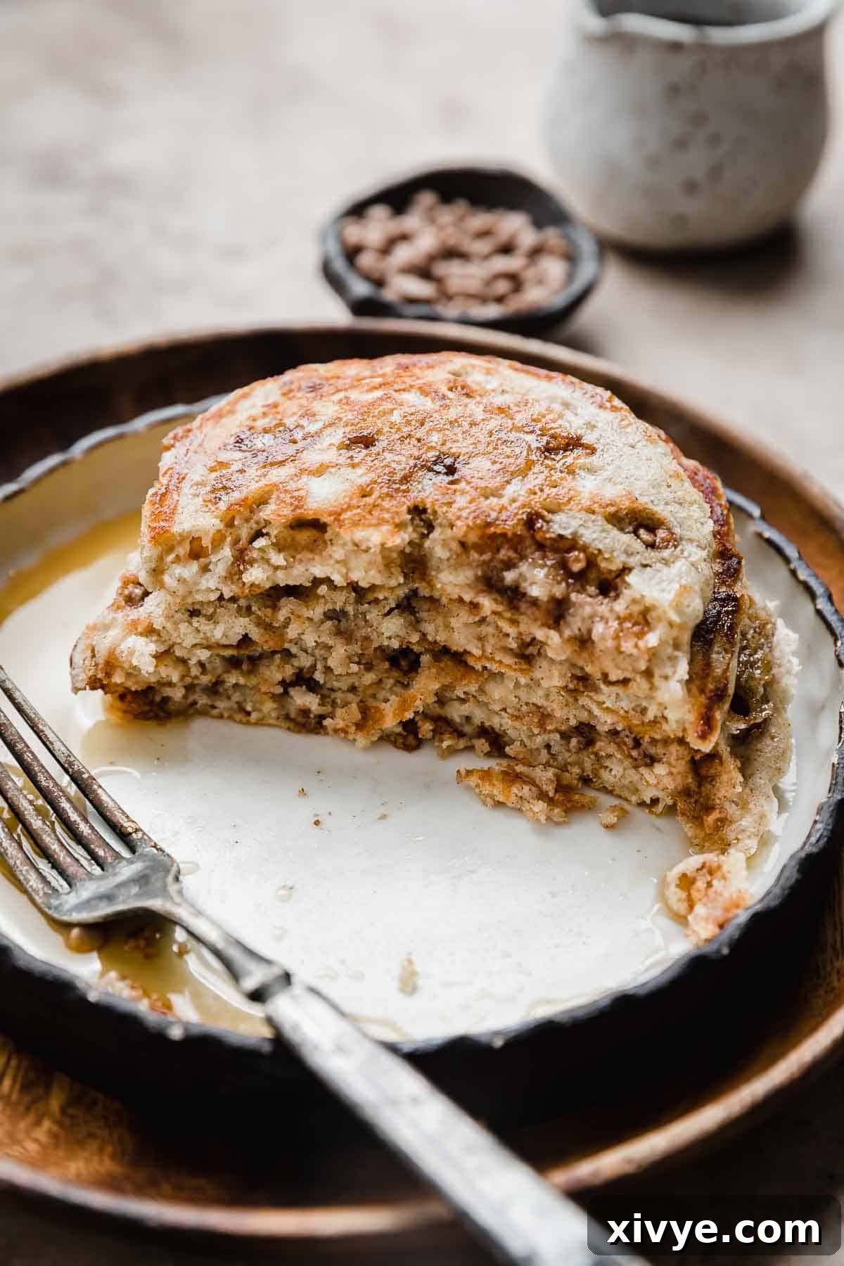 A stack of Cinnamon Chip Pancakes (cut in half) on a black rimmed white plate, with half the pancakes.