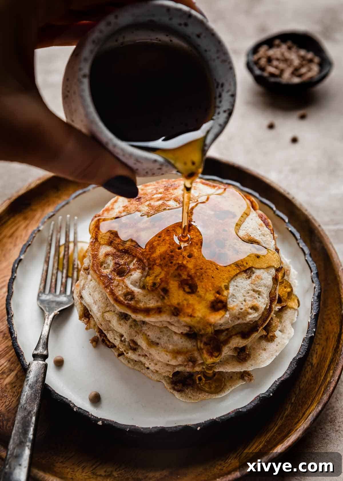 Maple syrup being poured overtop a stack of Cinnamon Chip Pancakes.
