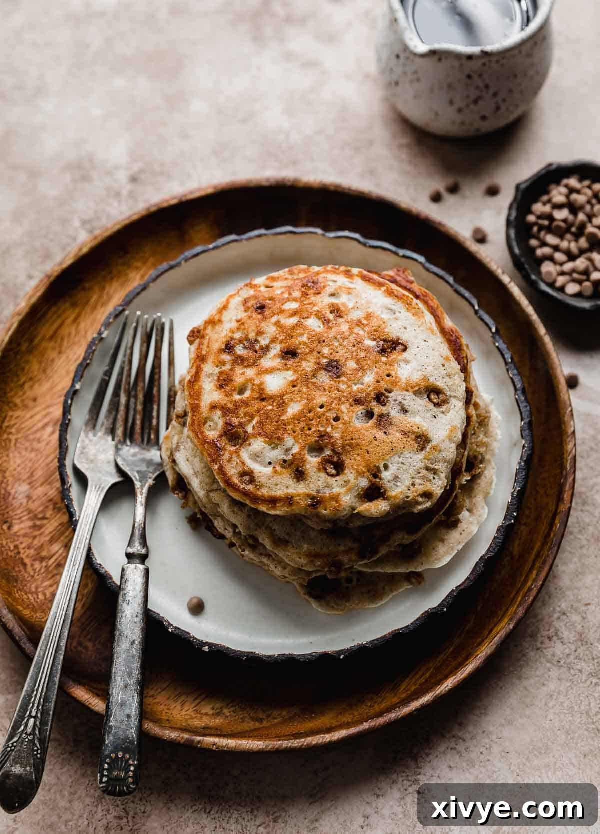 A stack of four Cinnamon Chip Pancakes on a brown wooden plate.
