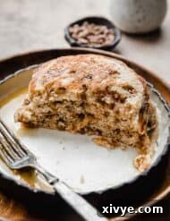 A stack of Cinnamon Chip Pancakes (cut in half) on a black rimmed white plate, with half the pancakes.