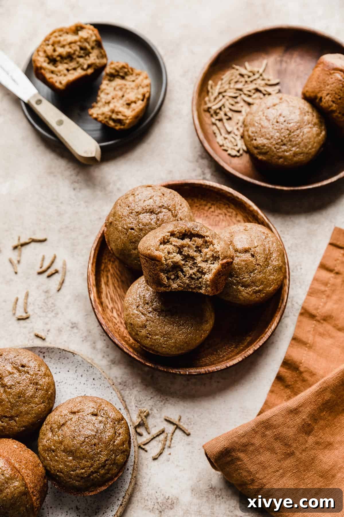 Hearty Buttermilk Bran Muffins 14 Four plates on a light brown textured background, each plate with two to three bran muffins on them.